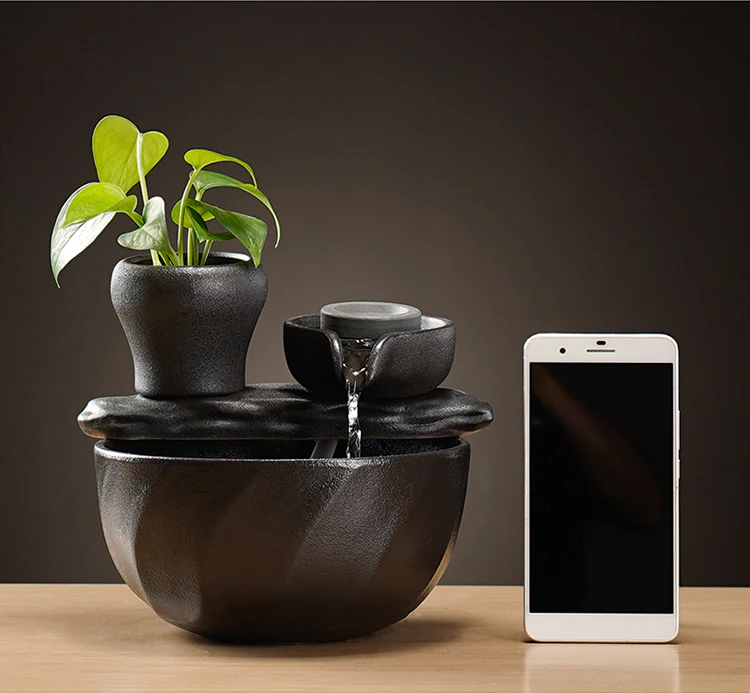 Ceramic tabletop fountain beside a smartphone for real-world scale